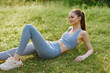 © SHOTPRIME STUDIO - Young fitness woman in blue activewear enjoying a peaceful moment on green grass in a sunny park, promoting relaxation and a healthy lifestyle