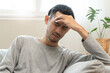 © Pormezz - Guy have headache and dizzy sitting on sofa at home