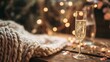 © Nan - A champagne flute with golden bubbles on a wooden table beside a cozy blanket and festive confetti.