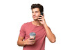 © luismolinero - Young handsome caucasian man over isolated background holding coffee to take away and a mobile