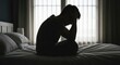 © ROY - Silhouette of a person sitting on a bed, head in hands