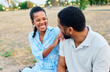 © Lumos sp - Portrait of a happy young couple, woman and  man,  black couple having fun sitting on bench and talking  holding hands and bonding in park outdoors