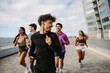 © Drobot Dean - A male athlete smiles and looks back as a group of four athletes run behind him
