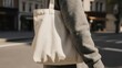 © ROUNDUP STD - Person walking with a blank tote bag in a city, close-up