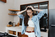 © SHOTPRIME STUDIO - Frustrated young woman in a kitchen, struggling with meal preparation, wearing a casual outfit and expressing emotions of stress and concern