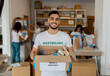 © Prostock-studio - A male volunteer at a charity center holds a box filled with food items. He works alongside colleagues, organizing donations to support poor and elderly individuals in the community.