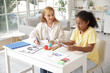 © Pixel-Shot - African-American girl with psychologist molding plasticine at table in office