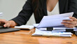 © AucArtStudio - Clutter paperwork office desk massy chaos overload stress work busy woman holding documents wooden desk with laptop and clipboard showing