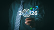 © PRIM - Businessman holding target board with 2026 text. Concept of corporate business goal, future strategy planning, financial success, marketing objective, and economy growth arrow.
