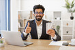 © sofiko14 - An Indian businessman smiles while holding cash and giving a thumbs up, showing his approval