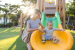© leungchopan - Mother taking baby to slide at playground