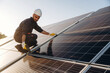 © standret - Drilling, installation process. Male solar engineer examining photovoltaic panels at a power station
