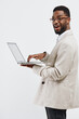 © SHOTPRIME STUDIO - Smiling man with beard wearing glasses and beige blazer holding laptop computer, looking at camera, happy expression, casual business attire, indoor studio shot, white background. People lifestyle