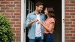 © Tanakorn - Young couple joyfully exchanges house keys, standing together at the welcoming brick entryway of their beautiful new home
