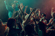 © master1305 - Energetic dance crowd with raised hands under colorful club lights. Concept of New Year night celebration, shared joy, nightlife energy, music driven freedom and modern party atmosphere.
