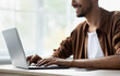 © Prostock-studio - A young man focuses on his work while typing on a laptop at a clean desk. Bright light filters through large windows, creating a cheerful atmosphere.