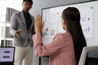 © Wasan - Businesswoman raising hand to ask a question during a presentation held by a businessman.