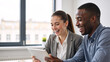 © Vyatcheslav - Happy diverse colleagues laughing together while looking at a tablet in the office. Positive teamwork and collaboration in a modern workplace