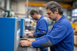 © gunzexx png and bg - Two focused men work diligently in a factory environment, showcasing concentration and teamwork in the industrial process of manufacturing and assembly with modern equipment.