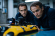 © gunzexx png and bg - Two engineers intensely examine a robotic underwater vehicle in a laboratory, highlighting the blend of technology and human ingenuity in advancing maritime exploration.