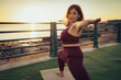 © Lomb - Serene curvy woman practicing yoga warrior pose at sunset focusing on breathing