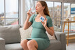© Pixel-Shot - Young pregnant woman holding paper with vitamin B3 and drinking water at home