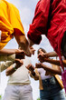 © Xavier Lorenzo - Vertical shot. Low angle view of united group of young people in circle holding hands. Community, support and teamwork concept with millennial people showing unity outdoors.