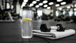 © Sohag - A refreshing water bottle with lemon and a dumbbell resting on a towel on the gym floor.