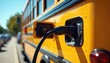 © Vadym - Yellow school bus plugs into electric charger on sunny day. Clean energy transport replaces gas vehicles for student commutes, preparing for future mobility.