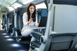 © Dejan - A smiling woman uses her bank card while working on a laptop in a train, highlighting the integration of finance into daily travel experiences.