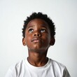 © Vadym - Young black boy with curly hair looks up thoughtfully. Child with curious expression, dark skin, white t-shirt on plain background. Childhood innocence, hope and dreams.