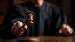 © QQPK14 - A judge in a black robe strikes a wooden gavel on a sound block, symbolizing authority and justice in a courtroom setting