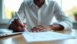 © Pete - Man fills out insurance claim form with pen at desk. Person completes paperwork for damage report, compensation request, legal agreement, or application.