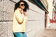 © halayalex - Beautiful woman with afro curls hairstyle.Smiling hipster model in yellow hoodie. Sexy carefree female posing on the street background in sunglasses. Cheerful and happy