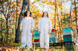© Cavan Images - Women beekeepers standing with beehives in autumn forest