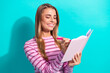 © deagreez - Young woman smiles while writing in notebook against teal background wearing pink striped shirt