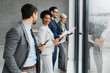 © Novak - Group of diverse business people standing by office window.