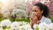 © Tiana_Geo - Young woman sneezing into tissue in a blooming park. Allergy symptom during spring season. Seasonal hay fever concept.