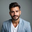 © Viktor - Young man with stylish haircut, groomed beard poses. Looks directly at camera with confident smile. Guy wears light blue blazer, white V-neck shirt. Modern studio portrait. Represents male beauty