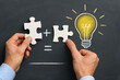 © nroy-ai - Hands holding puzzle pieces with chalk light bulb representing creativity teamwork problem solving and business innovation