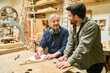 © Robert Kneschke - Experienced craftsman mentoring young apprentice in lumberyard workshop