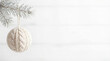 © Yuliya - White knitted Christmas bauble hanging on green pine branch with copy space. Demonstrating Color of the Year 2026 - Cloud Dancer.