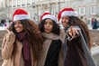 © Cata - Group of cheerful young women friends enjoying christmas holiday in madrid wearing santa hats and winter clothes