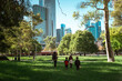 © Odua Images - A family joyfully walking in a lush park with a vibrant city skyline backdrop