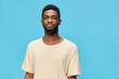 © SHOTPRIME STUDIO - Young African man in beige t shirt against a vibrant blue background, exuding confidence and calmness, perfect for lifestyle and fashion concepts
