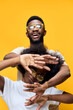 © SHOTPRIME STUDIO - Happy young African couple celebrating together, wearing stylish eyewear against a vibrant yellow background, showcasing joy and connection