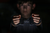 Young boy holding metal handcuffs in a dimly lit environment, showcasing a moment of tension and emotion, reflecting themes of confinement and freedom