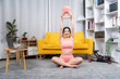 © Kritdanai - Body & Mind Harmony: A woman embraces her workout session at home. With a look of focus and joy, she lifts a kettlebell, a symbol of her dedication to well-being.