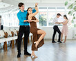 © JackF - With music, guy with girl in couple spins to rhythm of paso doble during lesson on parquet. Classes in mini-groups, participants of class enjoy movement, learn to control body in dance