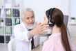 © New Africa - Hearing test. Doctor adjusting patient's audiometric headphones in clinic